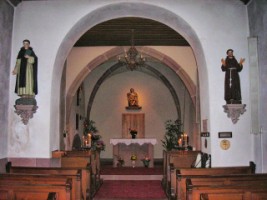 Les statues de saint Dominique et de saint François encadrent l'arcade qui sépare la nef du chœur de la Weiherkapelle de Bitche.