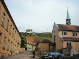 La maison Saint-Conrad (gauche), de même que l'ancien couvent des capucins et sa chapelle (droite) sont dominés par l'imposante silhouette de la citadelle de Bitche.