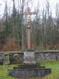 Une croix de cimetière en bois et en pierre trône au milieu du cimetière.