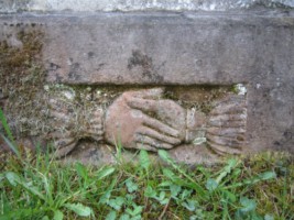 Deux mains se serrent au pied de la pierre tombale de la famille Brunagel-Schaming. Elles symbolisent vraisemblablement le contrat du mariage.