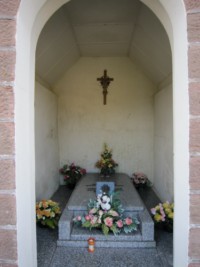 Remplaçant une statue de la Vierge de Pitié qui a été replacée à l'extérieur, la tombe de l'abbé Joseph Nullans occupe l'intérieur de la petite chapelle du cimetière.