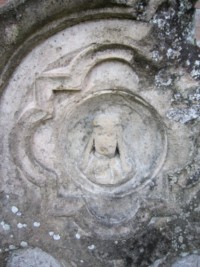 Comme sur la tombe de la famille Brunagel-Schaming, le visage du Christ couronné d'épines apparaît au sommet de la pierre tombale de cette tombe.