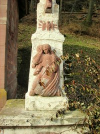 Le fût de la croix de chemin représente sainte Marie-Madeleine ainsi que la colombe du Saint-Esprit.