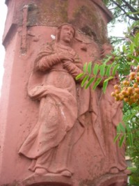 La Très Sainte Vierge est représentée à gauche du registre supérieur du fût-stèle.