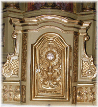 Un ostensoir est sculpté en bas-relief sur la porte du tabernacle inférieur.