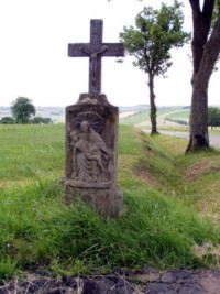 Une croix de chemin se dresse dans la rue des chevaliers, à la sortie du village de Kalhausen. Le fût-stèle représente une Pietà, tandis que le croisillon original a été remplacé par un nouveau croisillon en béton.