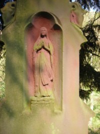 Une statuette de Notre-Dame de Lourdes est sculptée dans une niche.