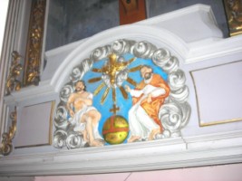 Un bas-relief, situé au pied de la croix monumentale du retable, nous présente les trois personnes divines de la Très Sainte-Trinité.