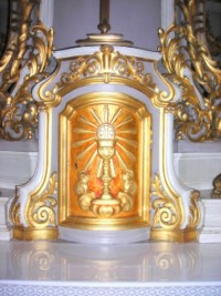 La porte du tabernacle est décorée d'un calice surmonté d'une hostie crucifère rayonnante.