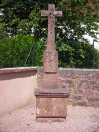 Une croix se dresse dans un angle du cimetière de Bousseviller, entourant encore la petite chapelle Sainte-Odile. En grès rose, elle représente deux saints personnages sur le registre supérieur du fût.