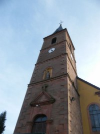 Le clocher de l'église Saint-Hubert présente une statue du saint patron dans une niche.