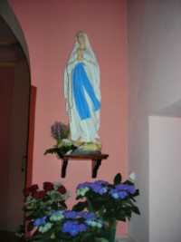 Une statue en plâtre de Notre-Dame de Lourdes est située à droite de l'arcade séparant la nef du chœur.