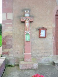 Une croix monumentale, datant de 1758, est adossée à la façade occidentale de la chapelle.