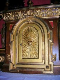 Le tabernacle est décoré d'un cœur crucifère couronné d'épines, dans une gloire.