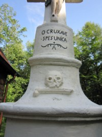 Un crâne et un tibia apparaissent au sommet du fût, accompagnés de l'oraison jaculatoire : " O crux ave spes unica ".