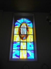 Un vitrail représente l'apparition de la Sainte Vierge à sainte Bernadette dans la cité de Lourdes, en 1858.