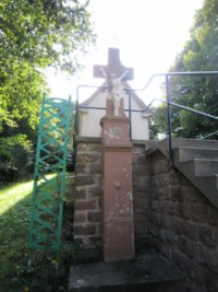 Une croix monumentale est érigée devant la chapelle de Dorst, au pied des escaliers.