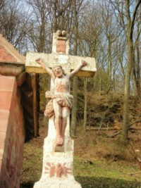 Le croisillon figure Notre-Seigneur Jésus-Christ en Croix, surmonté du titilus INRI et de deux têtes d'angelots ailées.